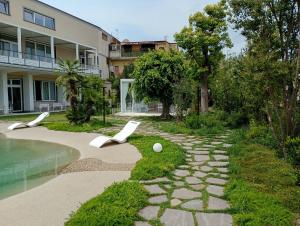a garden with two white chairs next to a pool at Hotel Elio in Marigliano