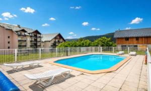 a swimming pool with two chairs and a fence at Vacancéole - Résidence La Croix Margot in Villard-de-Lans