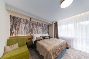 a bedroom with a bed and a green chair at Hotel Sitno Forest Resort - Family friendly in Banská Štiavnica +64 photos