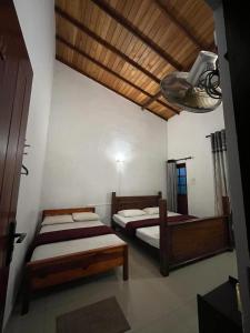 a bedroom with two beds and a wooden ceiling at Eightyseven guest and restaurant in Badulla