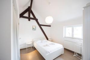 a white bedroom with a bed and a window at L'évasion - duplex in Zillisheim