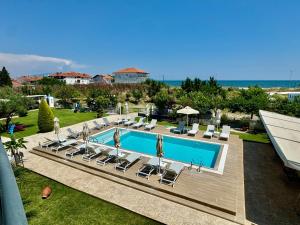a swimming pool with lounge chairs and the ocean at Littore Maris in Nea Vrasna