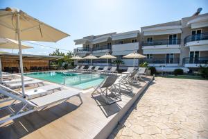 a swimming pool with lounge chairs and a hotel at Littore Maris in Nea Vrasna