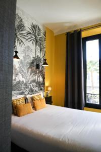 a bedroom with a bed with yellow walls and a window at Villa Pruly Hotel Cannes Centre in Cannes