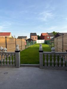 a fence with a view of a yard with houses at House for Tomorrowland in Rijweg