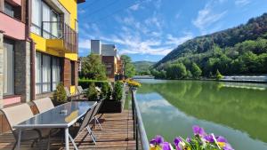 a balcony with a table and chairs next to a river at Waterside Houses in Ognyanovo