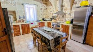 a kitchen with a table with chairs and a refrigerator at Razzett Pepprina Poppy Farm in Xagħra
