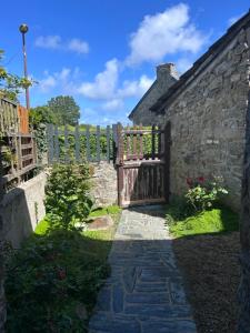 an entrance to a stone building with a wooden gate at La Roserie in Auderville