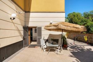 a patio with a table and a straw umbrella at B&B Pozzuoli - Suite Ermosa in Pozzuoli