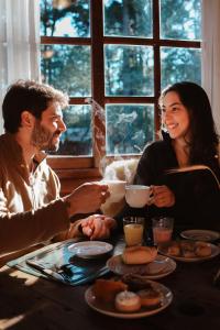a man and woman sitting at a table with food at Hotel Cabanas Glamour in Gramado