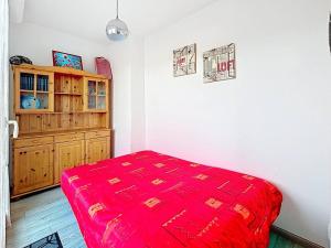 a bedroom with a red bed and a wooden cabinet at Charmant Studio Cabine 4 Pers, Balcons, Parking Privé, à 300m de la Plage de Merville-Franceville - FR-1-465-37 in Merville-Franceville-Plage