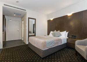 ein Hotelzimmer mit einem Bett und einem Stuhl in der Unterkunft Bankstown Motel 10 in Bankstown