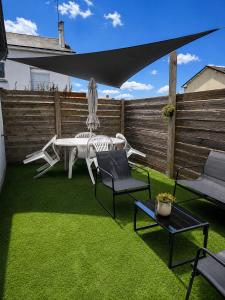 a patio with a table and chairs on grass at Le Studio, proche du puy in Saint-Pierre-Montlimart +2 photos