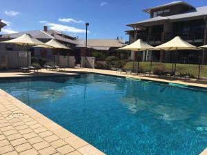 a large blue swimming pool with umbrellas and chairs at Apartment 36 in Margaret River Town