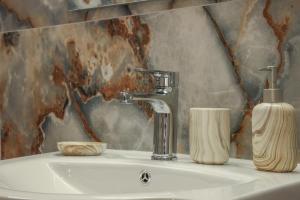 a bathroom sink with a faucet and a soap container at Cozy Twins - Terra in Kavála