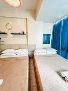 two beds in a room with blue curtains at Mactan Newtown Condo Rentals in Punta Engaño +65 photos
