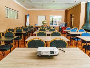 a room with tables and chairs with a projector on the table at Emoyeni Guest House in Nelspruit