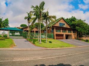a house with palm trees in front of a road at Emoyeni Guest House in Nelspruit