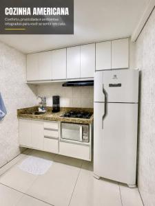 a kitchen with white cabinets and a refrigerator at Flat Pasárgada 404 in Vila Velha