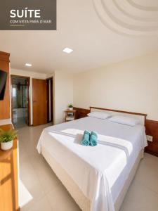 a bedroom with a bed with two blue shoes on it at Flat Pasárgada 404 in Vila Velha +13 photos
