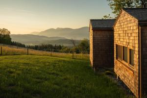 a house in a field with mountains in the background at Rosenholz Ferienhäuser in Köttmannsdorf