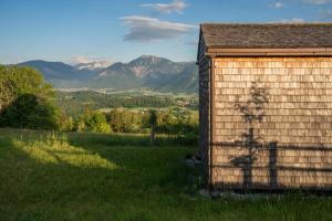 a building in a field with mountains in the background at Rosenholz Ferienhäuser in Köttmannsdorf