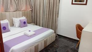 a hotel room with a bed with purple and white pillows at D'Mayor Suites, Gwarinpa in Gwarinpa