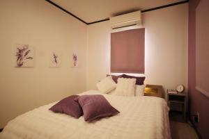 a bedroom with a bed with white sheets and purple pillows at Villa Vino in Fuefuki
