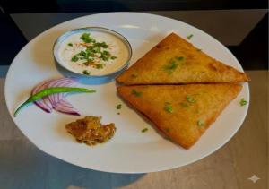a white plate with a piece of bread and a bowl of dip at Shri Hit Maya Dham in Vrindāvan