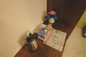 a table with a coffee pot and a newspaper and a flower at Hotel Ayodhya Inn in Lokāpur