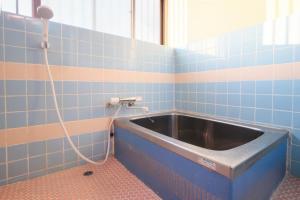 a bath tub in a blue tiled bathroom with a hose at Villa Vino in Fuefuki +34 photos