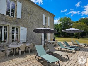 a deck with tables and chairs and umbrellas at Chadalou in Savignac-les-Églises