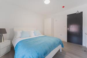 a white bedroom with a bed with a blue blanket at 4 Bedroom modern apartment in Birkenhead