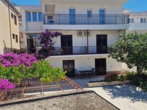 an apartment building with a balcony and purple flowers at Apartmani Batinović - Baška Voda in Baška Voda