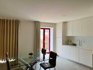 a kitchen with a glass table and chairs in a room at Apartamentos Fonte Velha in Ponte da Barca