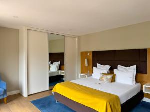 a hotel room with a large bed with a yellow blanket at Apartamentos Fonte Velha in Ponte da Barca