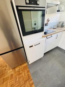 a kitchen with white cabinets and a stainless steel refrigerator at Le T3 Malpeaux – Arras Centre in Arras