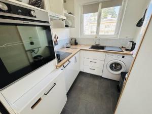 a small kitchen with white cabinets and a washer and dryer at Le T3 Malpeaux – Arras Centre in Arras