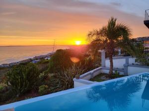 a sunset over the ocean from a villa with a swimming pool at Classical View Guesthouse in Mossel Bay