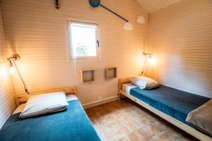 two beds in a room with wooden walls and a window at Domaine de Guillaume Chalet 4 Pers in Auquainville +77 photos