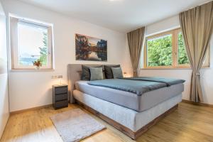 a bedroom with a bed and two windows at FeWo Iller im Allgäu in Sonthofen