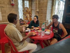 a group of people sitting around a table eating pizza at ROAMERS INN Backpackers Hostel in Kolkata