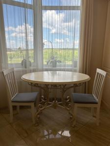 a table and two chairs in front of a window at Classic Contemporary Apartament in Chişinău +6 photos