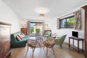 a living room with a green couch and chairs at Maison Des Hôtes - Dordogne in Saint-Crépin-dʼAuberoche