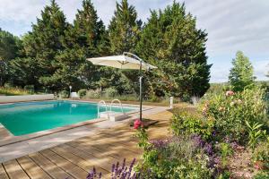 a pool with an umbrella next to a wooden deck at Maison Des Hôtes - Dordogne in Saint-Crépin-dʼAuberoche