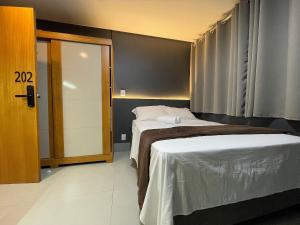 a hotel room with two beds and a door at Real Grandeza - Studios modernos in Aparecida de Goiânia