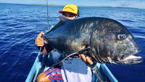 a man holding a large fish in the ocean at Mentawai Tribe Experience & Private Beach Camp in Pulau Masilo