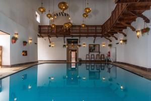 an indoor pool with blue water in a building with chandeliers at Beyt Al Salaam in Zanzibar City