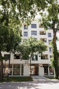a white building with trees in front of it at Una Lux Apartment in Sombor
