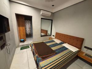 a bedroom with a bed and a mirror at Shree Hariraj Guest House in Vapi